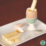 A boiled egg with a cheese stick inside on a plate