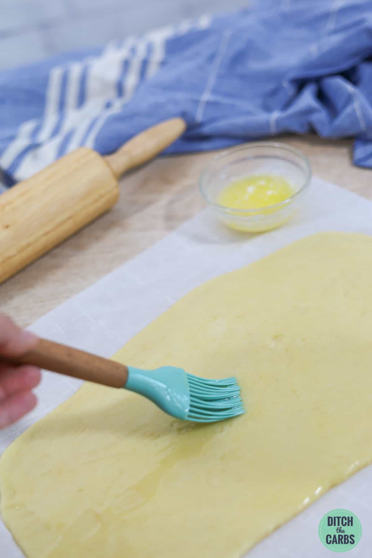 adding melted butter to cinnamon roll dough
