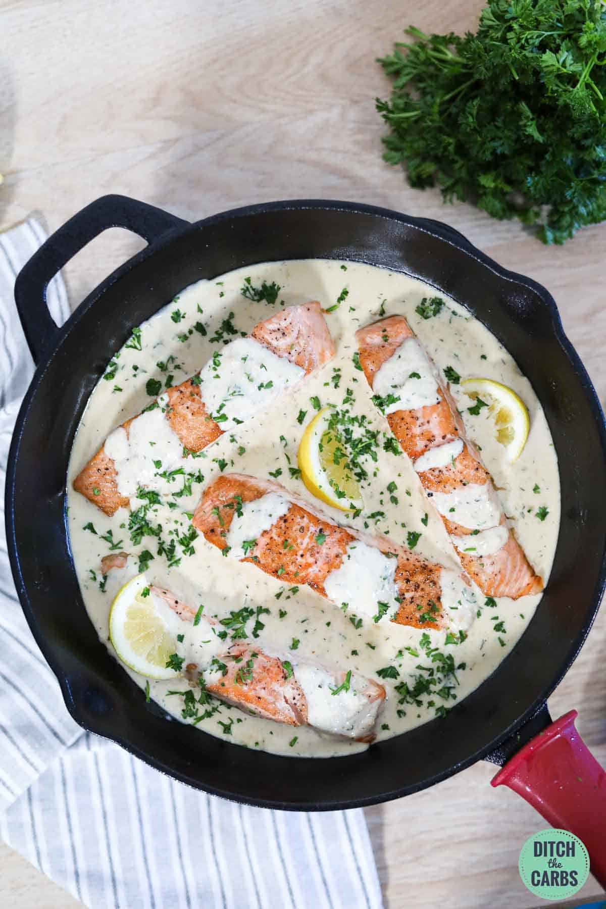 a cast iron skillet with salmon and creamy garlic sauce