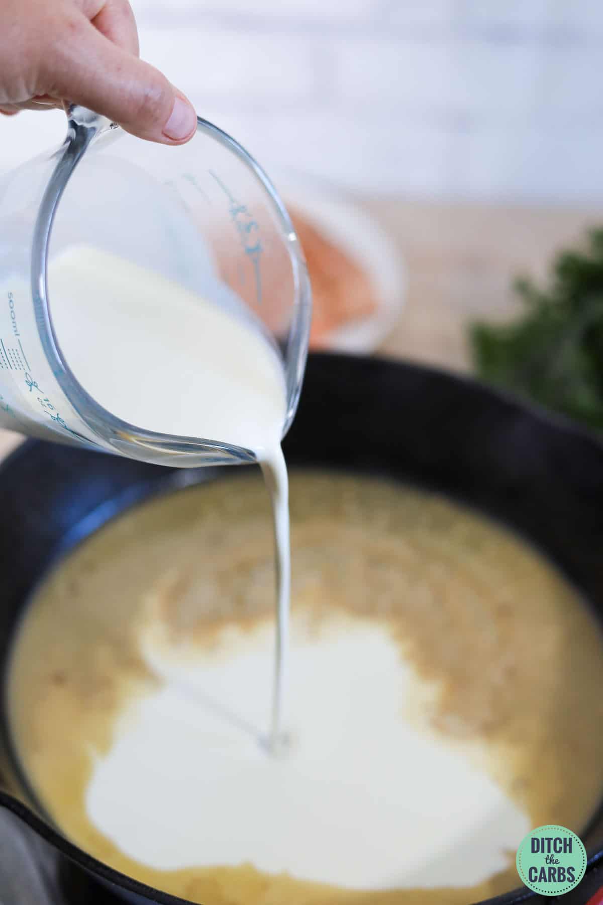 heavy cream being poured into garlic butter sauce