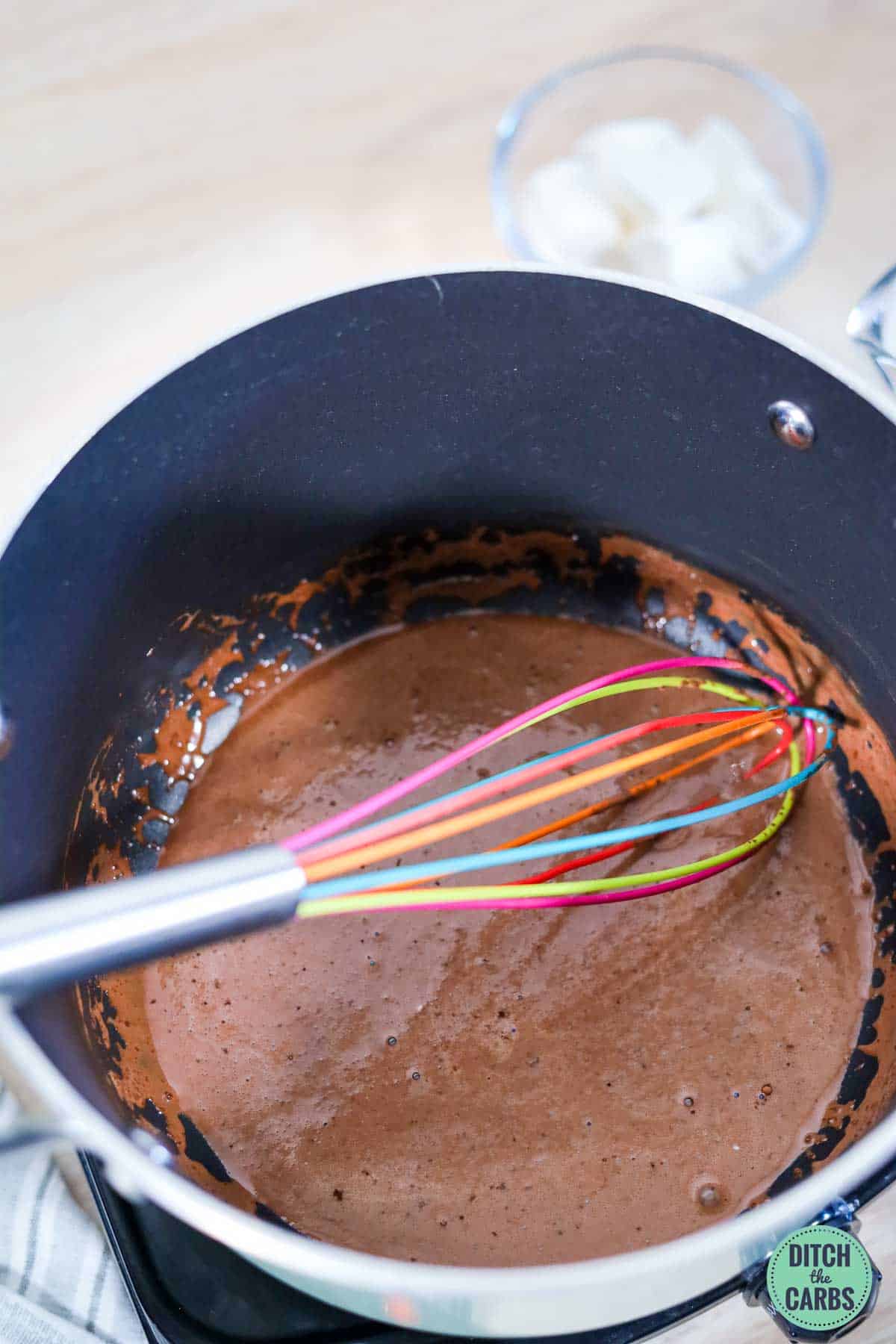 a coloured whisk in a pot of hot chocolate