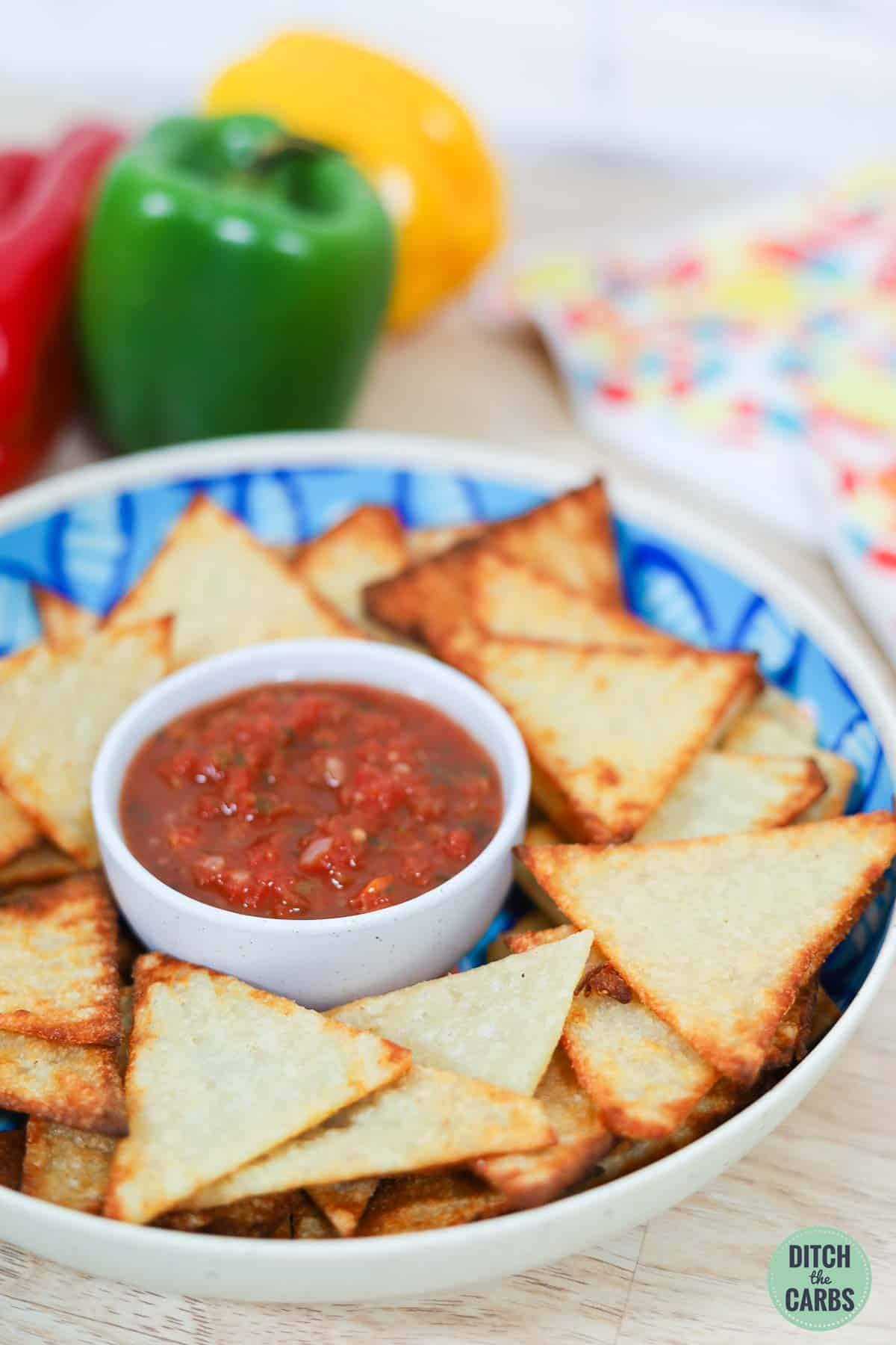 crispy tortilla chips in a serving bowl with a dish of fresh salsa in the middle.