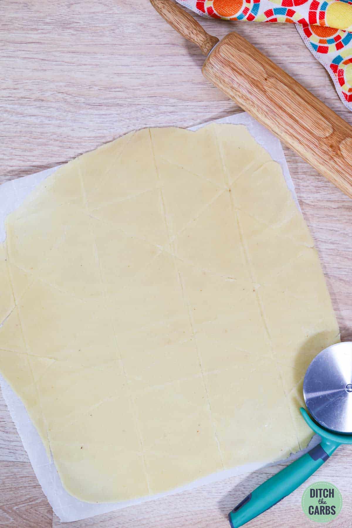 Dough for keto tortilla chips rolled out and cut into triangles with a pizza cutter.