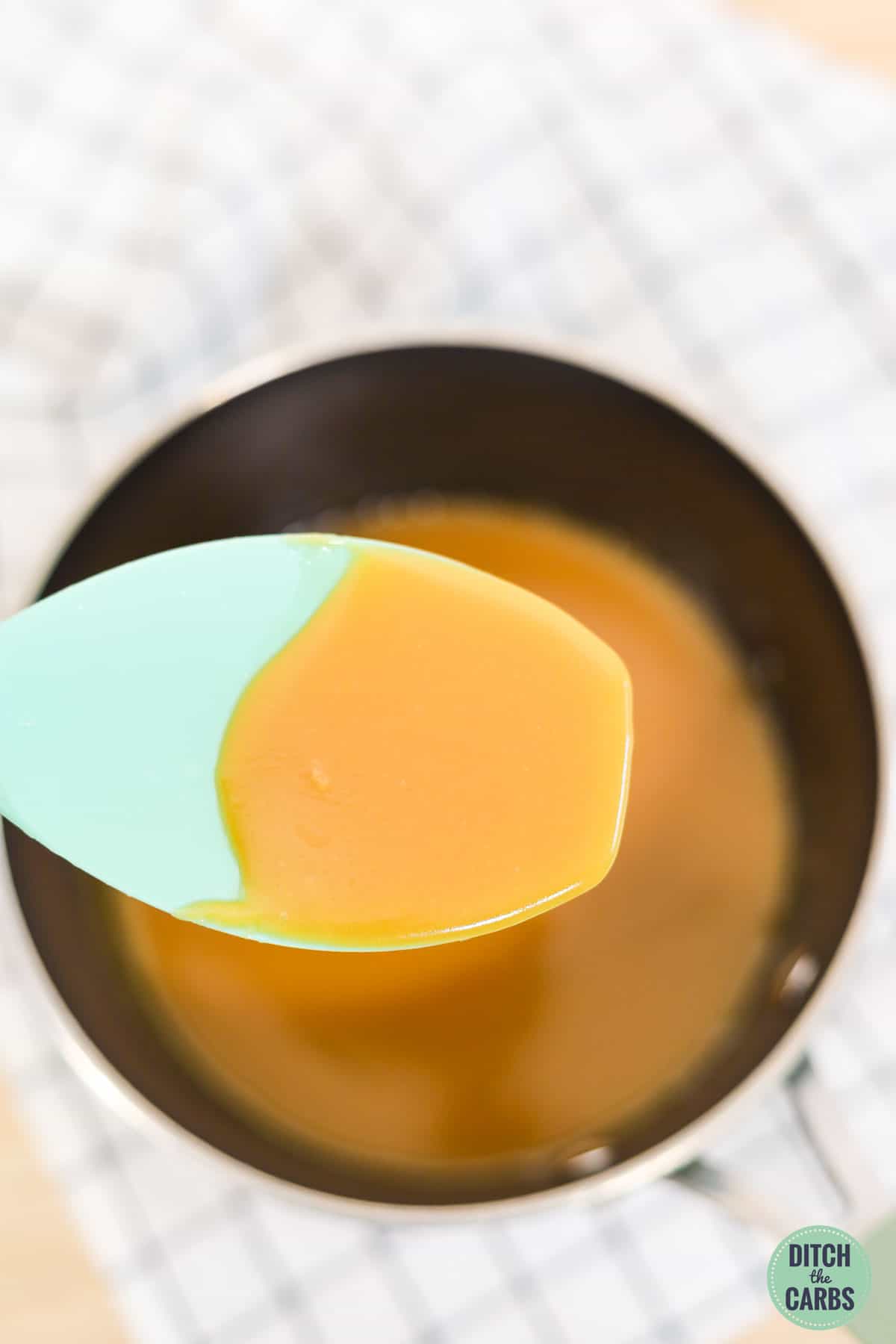 a mixing spoon coated in sugar free caramel sauce