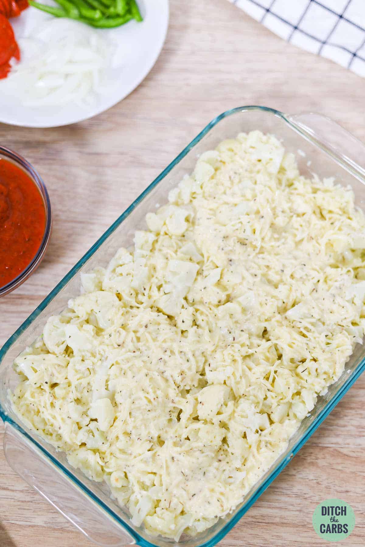 steamed cauliflower chopped in a baking dish and covered in cheese