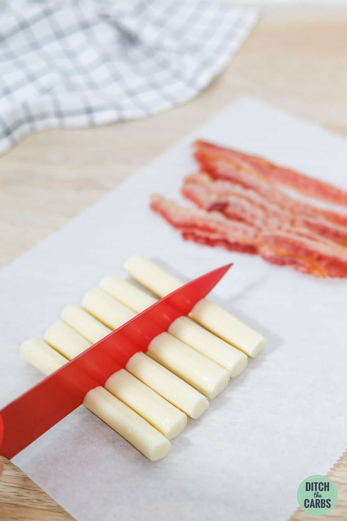 A knife cutting cheese sticks in half