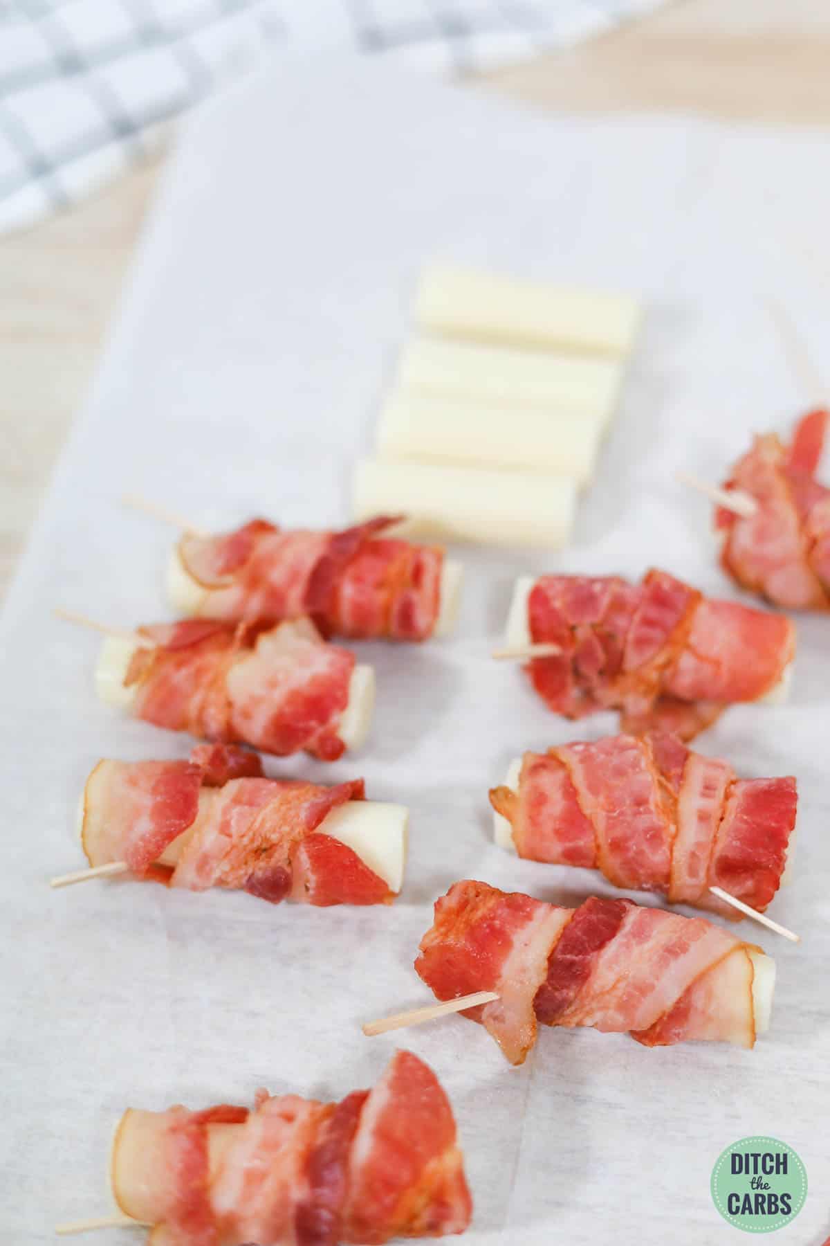 each cheese stick wrapped with bacon and pinned with a toothpick.