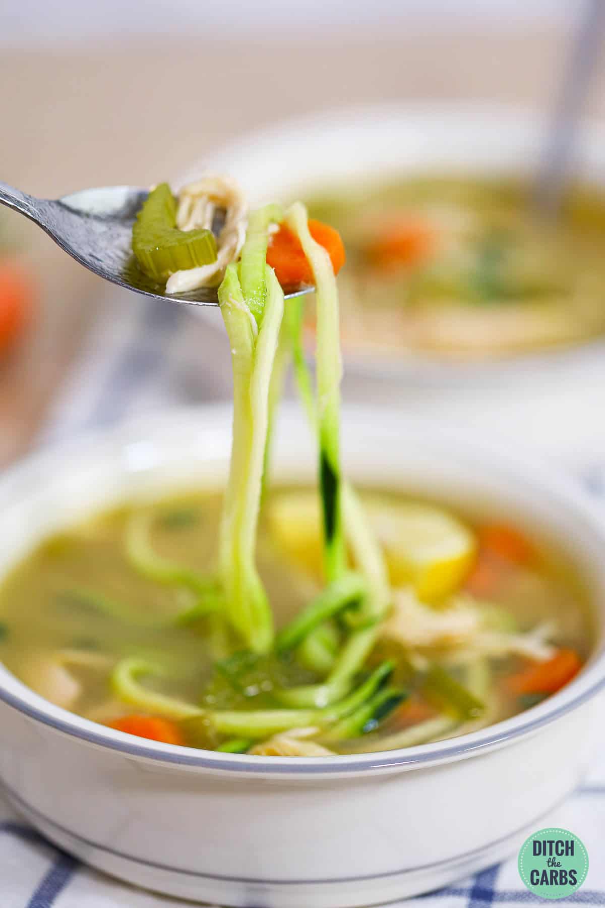 a spoon lifting a bite of veggies from soupy broth