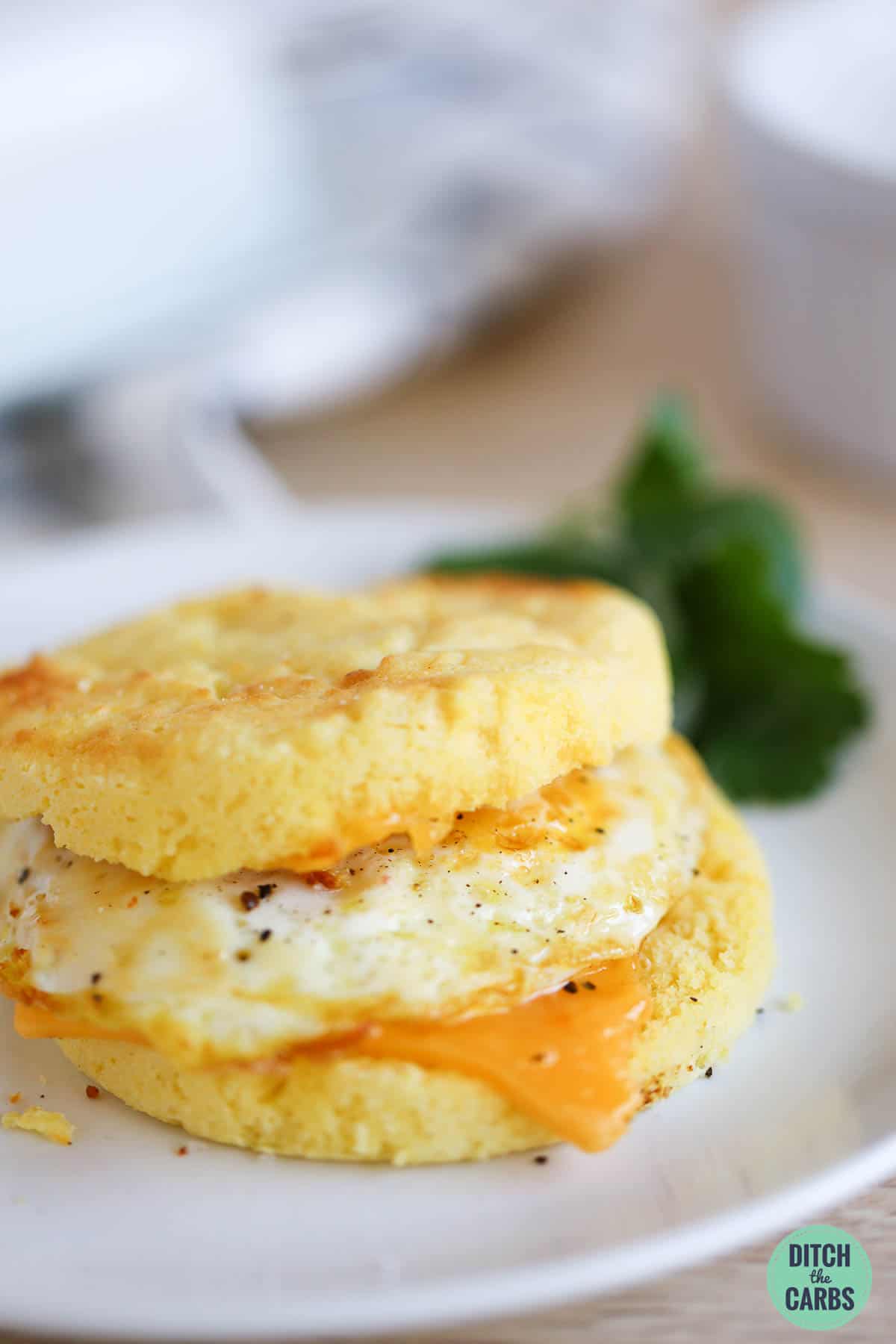 Low-carb English muffin topped with a fried egg and slice of cheese to make an egg breakfast sandwich.