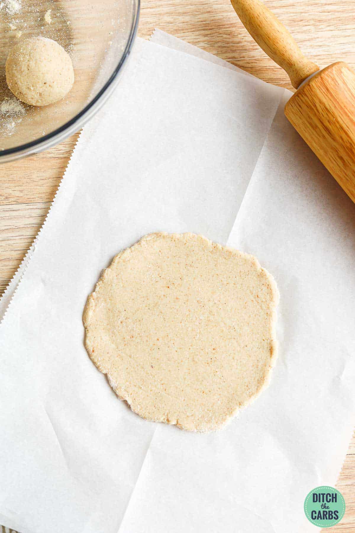 Low-carb pita bread rolled out into a circle on a piece of parchment paper.
