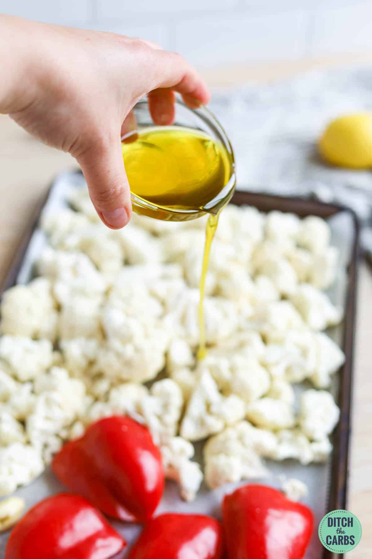 Pouring olive oil over the cauliflower and red pepper.