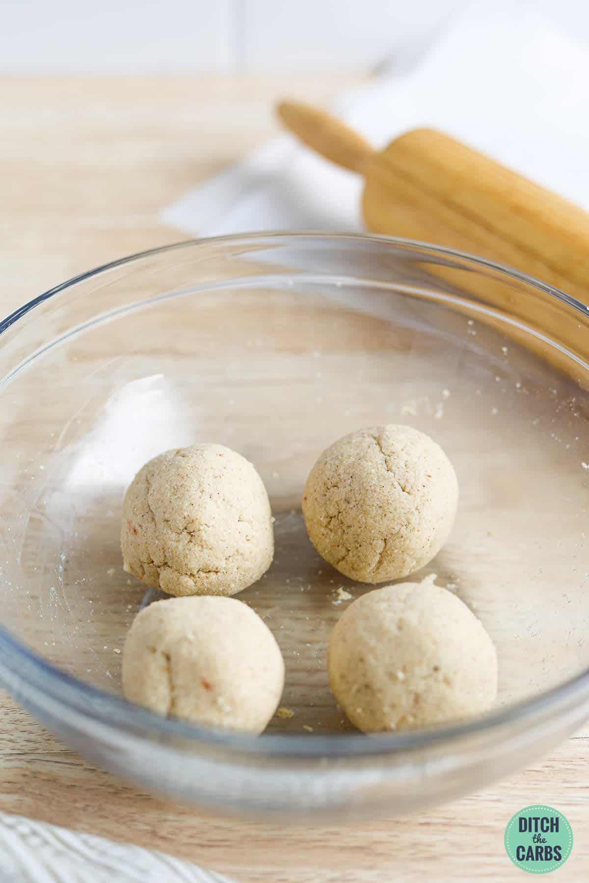 4 balls of low-carb pita bread dough in a glass bowl.