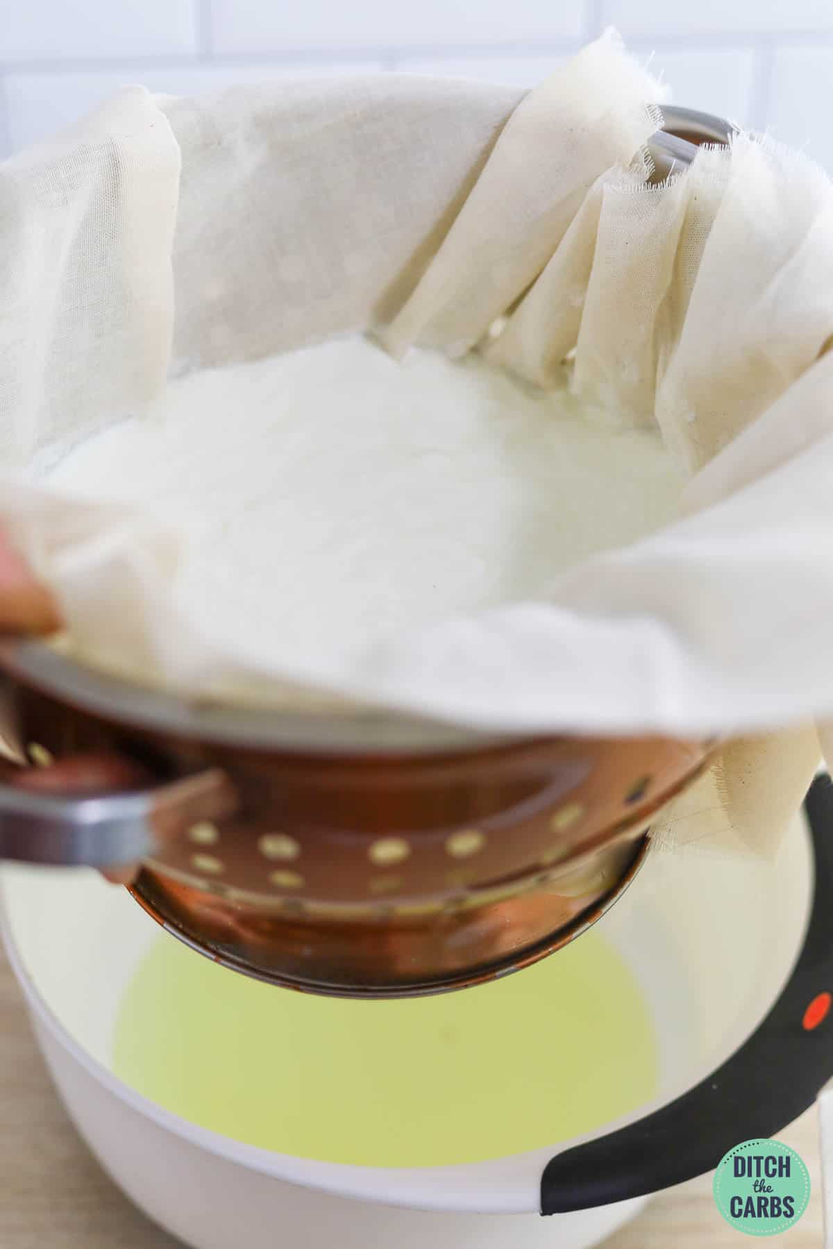 Straining the whey from the yogurt using a colander and cheesecloth.