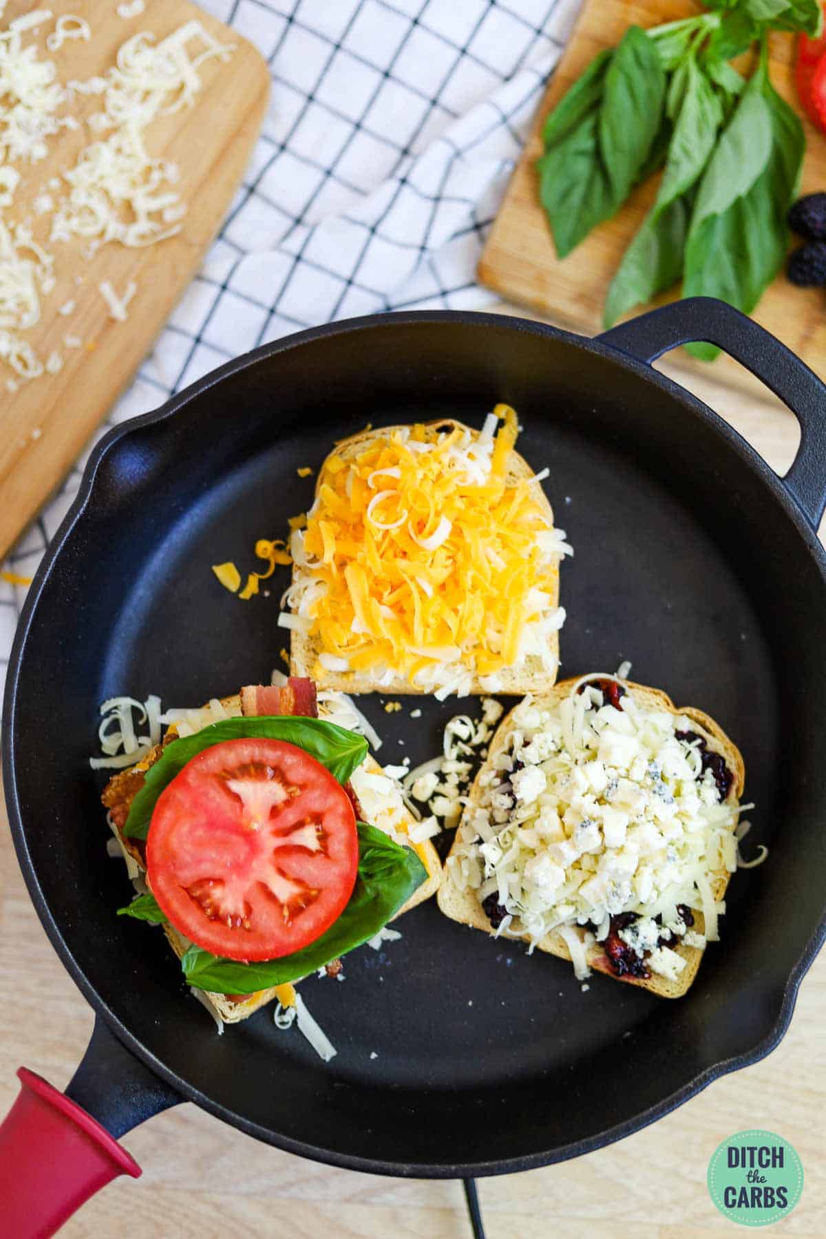 Shredded cheese and toppings layered over 3 pieces of butter keto bread in a cast iron skillet to make grilled cheese sandwiches.