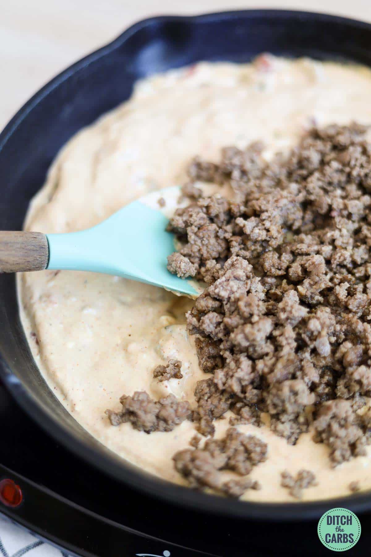 Mixing the cooked ground beef back into the queso.