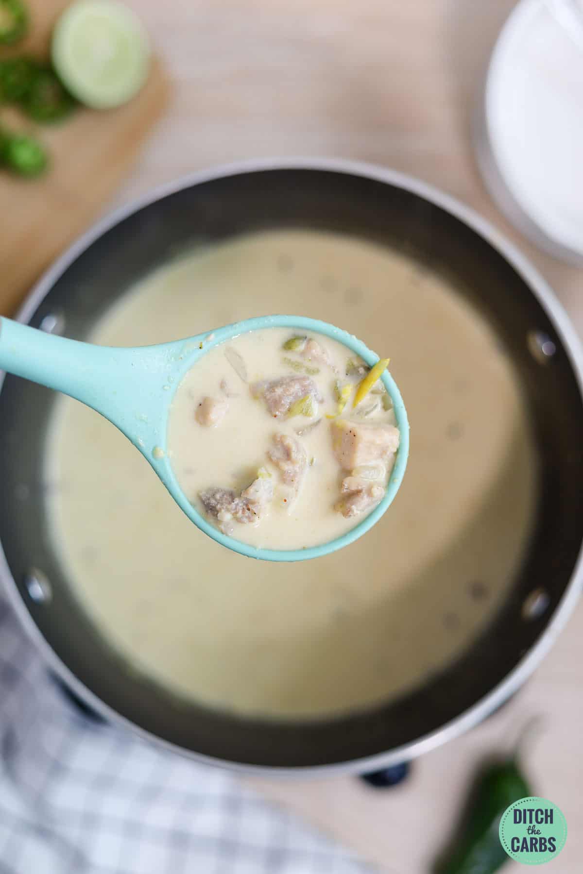 A ladle if lifting a spoonful of white chicken chili to be served.